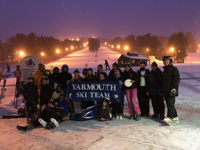 Team in front of ski mountain with banner