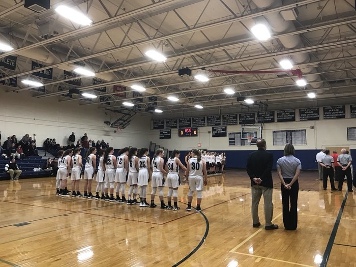 girls basketball players standing for the national anthem